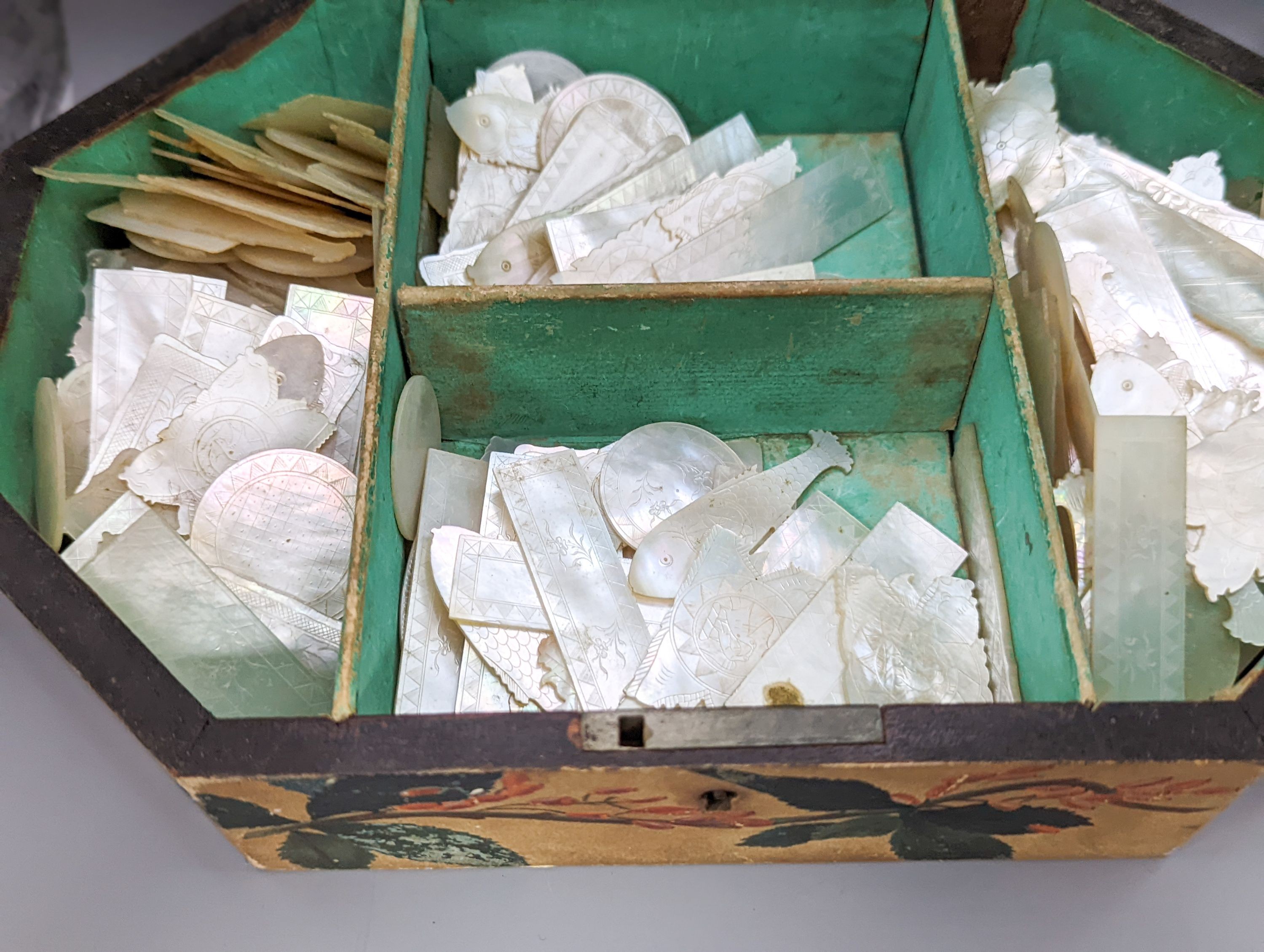 A collection of 19th century Cantonese etched mother of pearl gaming counters, within a lidded octagonal box, 26cm